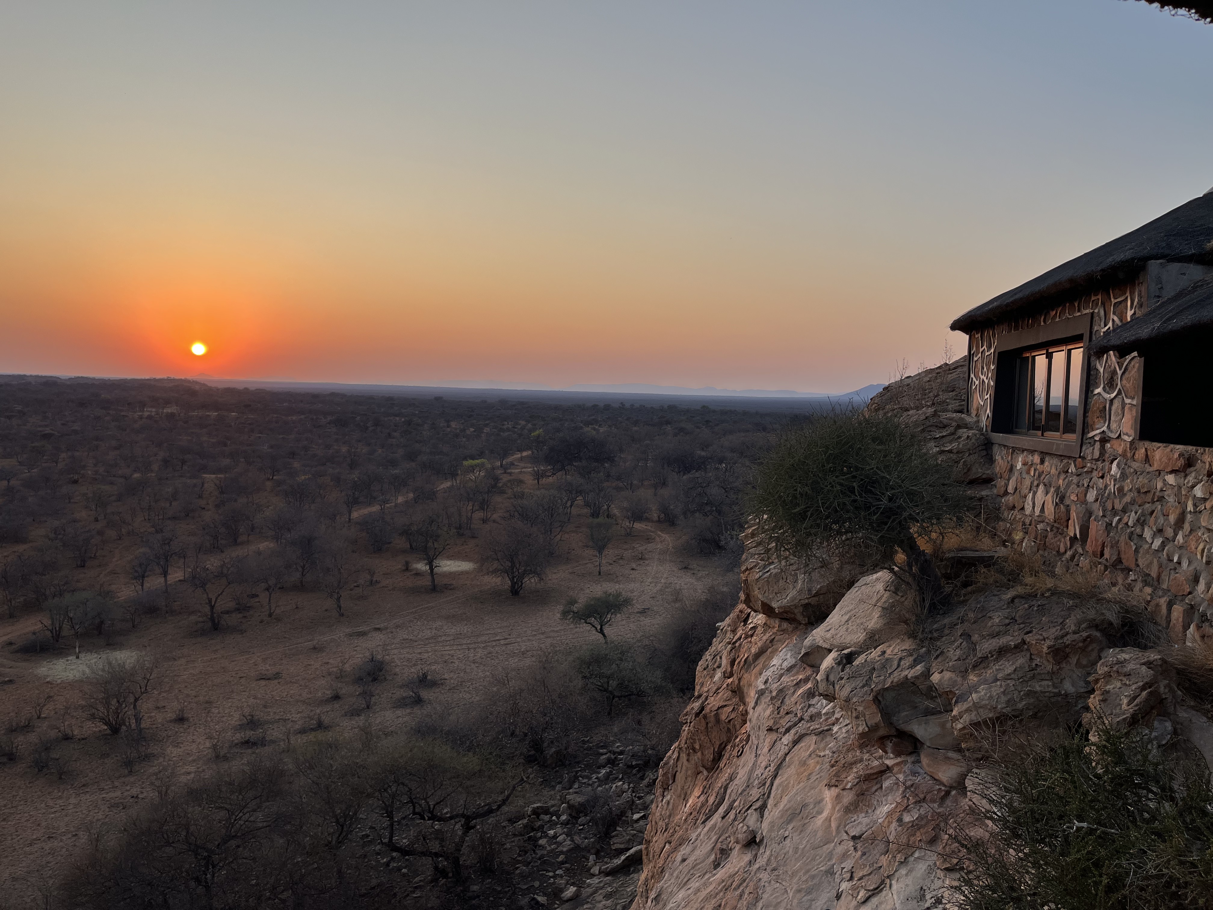 Stone-clad JutLand lodge perched on a clifftop, glowing in the sunset over the bushveld